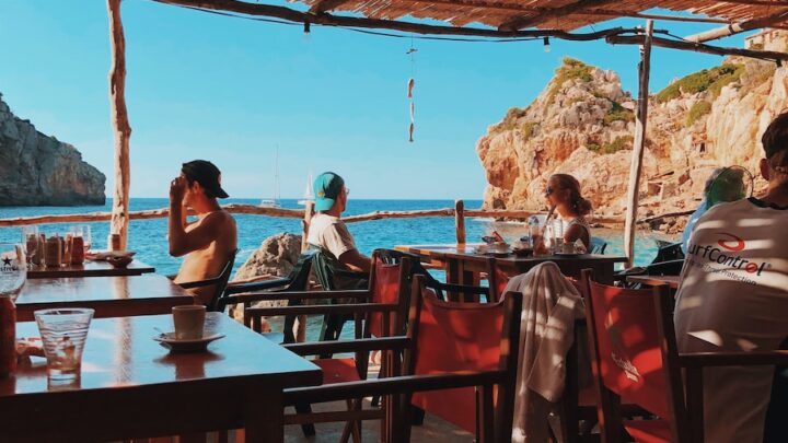 man and woman sitting on chair in front of table beside body of water