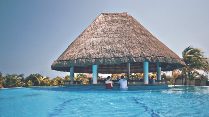 man and woman in blue pool under cottage at daytime